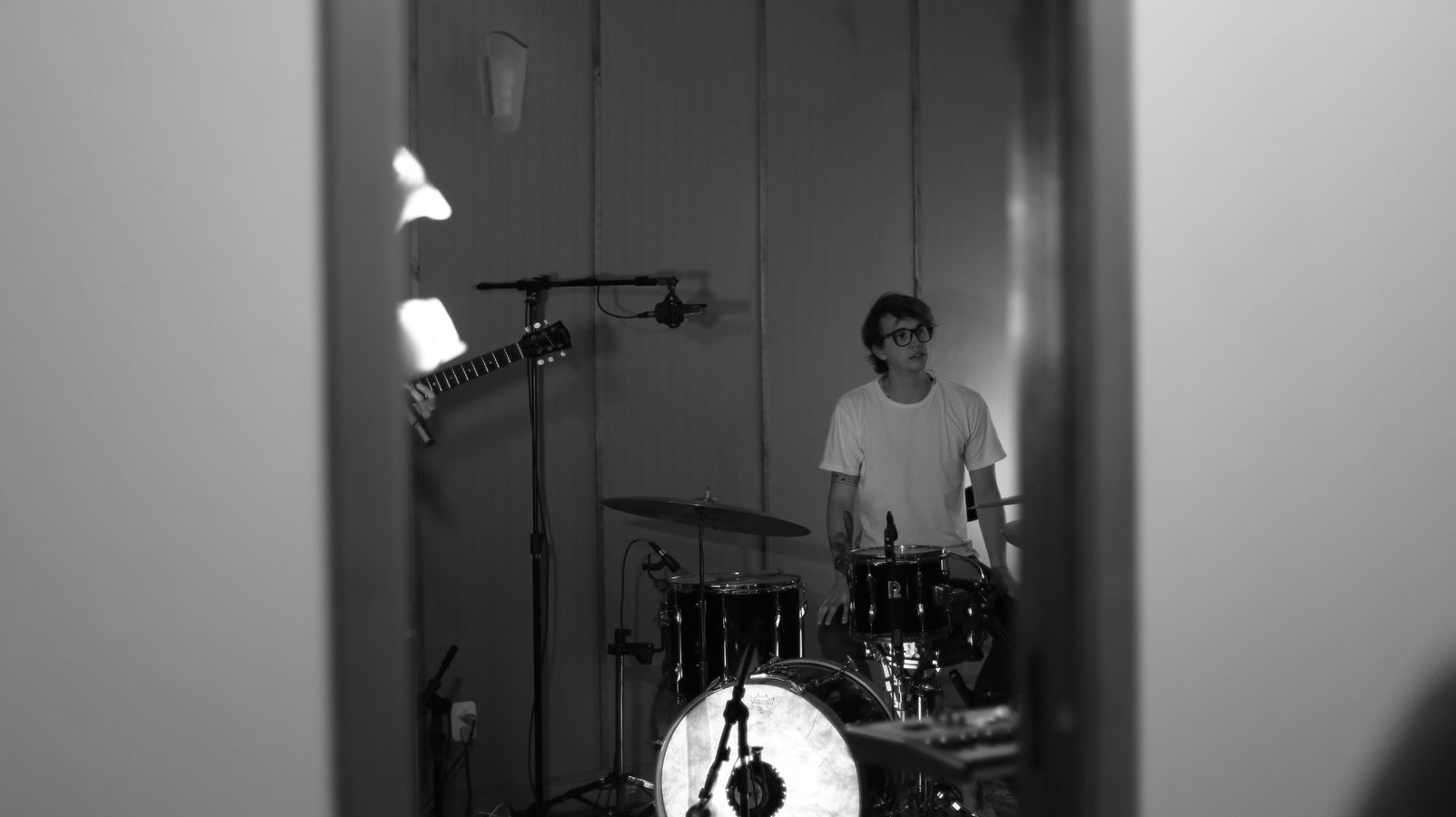 Baterista visto por uma porta entreaberta, durante a gravação.